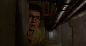 Movie still from “Barking Dogs Never Bite” (2000), directed by Bong Joon Ho – A man with glasses leaning against a wall; Close Up shot, Low angle