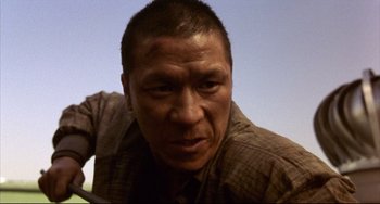 Movie still from “Barking Dogs Never Bite” (2000), directed by Bong Joon Ho – A man's face in a plaid shirt; Close Up shot, Low angle