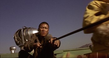 Movie still from “Barking Dogs Never Bite” (2000), directed by Bong Joon Ho – A man holding a large metal object in front of a building; Medium shot, Low angle