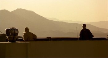 Movie still from “Barking Dogs Never Bite” (2000), directed by Bong Joon Ho – Two men sitting on a ledge looking out at the mountains; Extreme Wide shot, Low angle