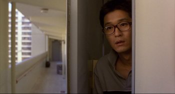 Movie still from “Barking Dogs Never Bite” (2000), directed by Bong Joon Ho – A man with glasses looking out of a window; Close Up shot, Over the shoulder angle