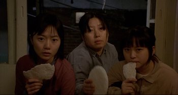 Movie still from “Barking Dogs Never Bite” (2000), directed by Bong Joon Ho – A group of people sitting next to each other holding food; Close Up shot, High angle
