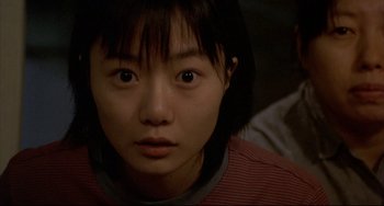 Movie still from “Barking Dogs Never Bite” (2000), directed by Bong Joon Ho – A young asian girl looking at the camera; Close Up shot, Over the shoulder angle