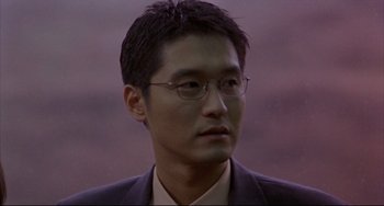 Movie still from “Barking Dogs Never Bite” (2000), directed by Bong Joon Ho – A person wearing glasses and a suit; Close Up shot, High angle