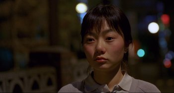 Movie still from “Barking Dogs Never Bite” (2000), directed by Bong Joon Ho – A young asian woman looking at the camera; Close Up shot, High angle