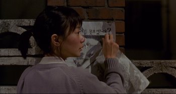Movie still from “Barking Dogs Never Bite” (2000), directed by Bong Joon Ho – A woman is writing on a piece of paper; Close Up shot, High angle