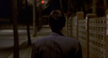 Movie still from “Barking Dogs Never Bite” (2000), directed by Bong Joon Ho – A man wearing a suit walking down a street; Close Up shot, Over the shoulder angle