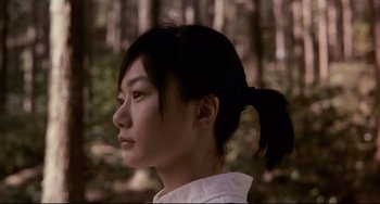 Movie still from “Barking Dogs Never Bite” (2000), directed by Bong Joon Ho – A woman with a ponytail in the woods; Close Up shot, Low angle