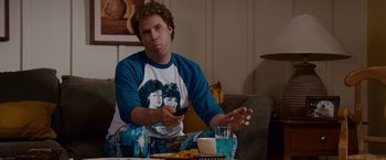 Movie still from “Step Brothers” (2008), directed by Adam McKay – A man sitting at a table holding a cell phone; Medium shot, High angle