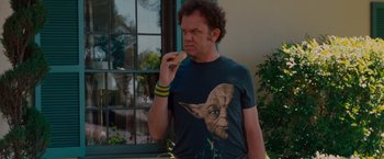 Movie still from “Step Brothers” (2008), directed by Adam McKay – A man in a star wars t - shirt is eating a donut; Medium shot, Over the shoulder angle