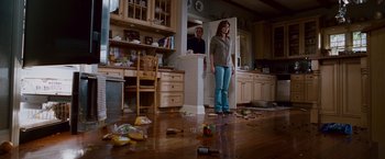 Movie still from “Step Brothers” (2008), directed by Adam McKay – A woman standing in a cluttered kitchen next to an open door; Wide shot, High angle