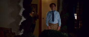 Movie still from “Step Brothers” (2008), directed by Adam McKay – A man standing in front of a door wearing a tie; Medium shot, Over the shoulder angle