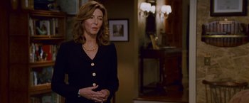 Movie still from “Step Brothers” (2008), directed by Adam McKay – A woman standing in a living room wearing a black jacket; Medium shot, Over the shoulder angle