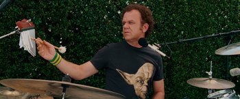Movie still from “Step Brothers” (2008), directed by Adam McKay – A man in a t - shirt is playing a drum; Close Up shot, Over the shoulder angle
