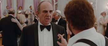 Movie still from “Barney's Version” (2010), directed by Richard J. Lewis – An older man in a tuxedo talking to a man holding a cigar; Close Up shot, Over the shoulder angle