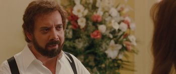 Movie still from “Barney's Version” (2010), directed by Richard J. Lewis – A man with a beard is standing in front of flowers; Close Up shot, Over the shoulder angle