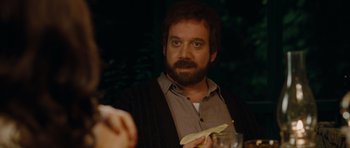 Movie still from “Barney's Version” (2010), directed by Richard J. Lewis – A man sitting at a dinner table holding a piece of paper; Close Up shot, Over the shoulder angle