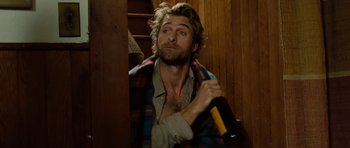 Movie still from “Barney's Version” (2010), directed by Richard J. Lewis – A man holding a bottle of wine in his hand; Medium shot, Low angle