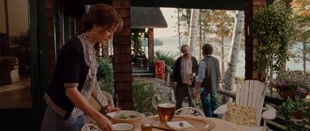 Movie still from “Barney's Version” (2010), directed by Richard J. Lewis – A group of people standing around a table with plates of food on top of it; Wide shot, Over the shoulder angle
