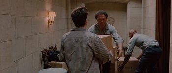Movie still from “Barney's Version” (2010), directed by Richard J. Lewis – A man is holding a box while another man looks at him in the mirror; Medium shot, Over the shoulder angle