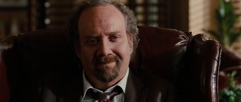 Movie still from “Barney's Version” (2010), directed by Richard J. Lewis – A man with a beard and a suit sitting in a chair; Close Up shot, Over the shoulder angle