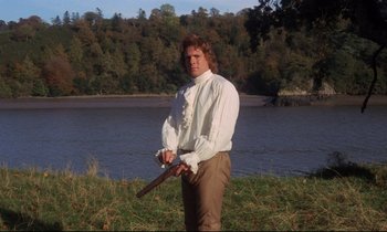 Movie still from “Barry Lyndon” (1975), directed by Stanley Kubrick – A man in a white shirt and brown pants holding a gun in his hands; Medium shot, Low angle