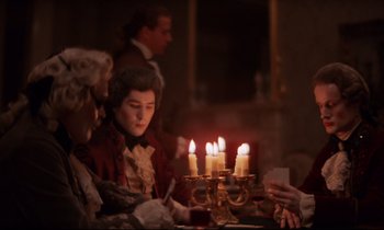 Movie still from “Barry Lyndon” (1975), directed by Stanley Kubrick – A group of people sitting around a table with candles; Medium shot, Over the shoulder angle