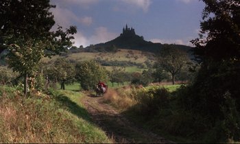 Movie still from “Barry Lyndon” (1975), directed by Stanley Kubrick – Two people are riding a horse in a field with a castle in the background; Extreme Wide shot, High angle