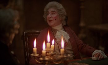Movie still from “Barry Lyndon” (1975), directed by Stanley Kubrick – A man sitting in front of a group of lit candles; Medium shot, Over the shoulder angle