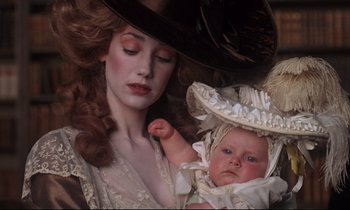 Movie still from “Barry Lyndon” (1975), directed by Stanley Kubrick – A woman holding a baby wearing a hat; Close Up shot, High angle