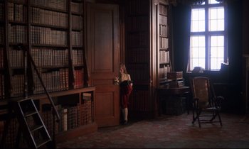 Movie still from “Barry Lyndon” (1975), directed by Stanley Kubrick – A woman standing in front of bookcases in a library; Wide shot, High angle