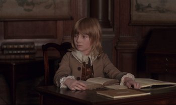 Movie still from “Barry Lyndon” (1975), directed by Stanley Kubrick – A girl sitting at a table reading a book; Medium shot, High angle