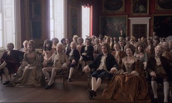 Movie still from “Barry Lyndon” (1975), directed by Stanley Kubrick – A large group of people sitting in chairs in a room; Wide shot, High angle