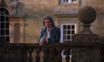 Movie still from “Barry Lyndon” (1975), directed by Stanley Kubrick – A young man leaning on a railing in front of a building; Medium shot, Low angle