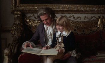 Movie still from “Barry Lyndon” (1975), directed by Stanley Kubrick – A man sitting next to a little girl reading a book; Medium shot, High angle