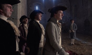 Movie still from “Barry Lyndon” (1975), directed by Stanley Kubrick – A group of men in period clothing standing in a room; Medium shot, Low angle