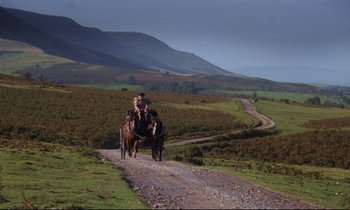 Movie still from “Barry Lyndon” (1975), directed by Stanley Kubrick – A man and a woman riding a horse and carriage down a dirt road; Extreme Wide shot, High angle