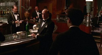 Movie still from “Barton Fink” (1991), directed by Joel Coen – A man in a tuxedo sitting at a bar; Medium shot, Over the shoulder angle