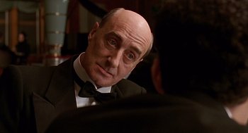 Movie still from “Barton Fink” (1991), directed by Joel Coen – A bald man in a black suit and a bow tie; Close Up shot, Over the shoulder angle