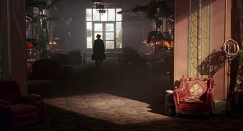 Movie still from “Barton Fink” (1991), directed by Joel Coen – A person standing in front of an open window in a living room; Wide shot, Over the shoulder angle