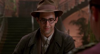 Movie still from “Barton Fink” (1991), directed by Joel Coen – A man wearing a hat and glasses and a suit; Close Up shot, Over the shoulder angle