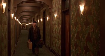 Movie still from “Barton Fink” (1991), directed by Joel Coen – A man walking down a hallway with a suitcase; Wide shot, High angle