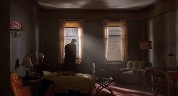 Movie still from “Barton Fink” (1991), directed by Joel Coen – A man standing in a room looking out of a window; Wide shot, Low angle
