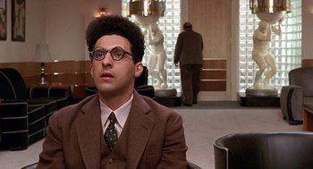 Movie still from “Barton Fink” (1991), directed by Joel Coen – A man in a suit and tie sitting in front of a statue; Close Up shot, Over the shoulder angle