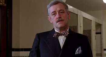 Movie still from “Barton Fink” (1991), directed by Joel Coen – An older man wearing a suit and a bow tie; Close Up shot, Low angle