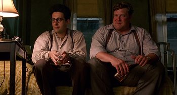 Movie still from “Barton Fink” (1991), directed by Joel Coen – A couple of men sitting next to each other on a couch; Medium shot, Low angle