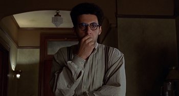Movie still from “Barton Fink” (1991), directed by Joel Coen – A man with glasses is standing in front of a door; Close Up shot, Low angle