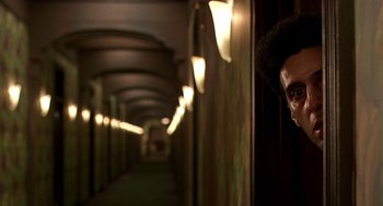 Movie still from “Barton Fink” (1991), directed by Joel Coen – A man standing in a dark hallway looking at the camera; Close Up shot, Over the shoulder angle