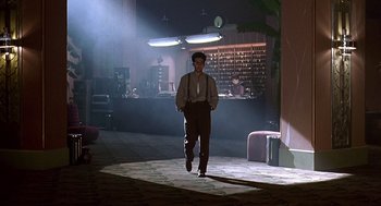 Movie still from “Barton Fink” (1991), directed by Joel Coen – A man in a suit and tie walking in a room; Wide shot, Low angle