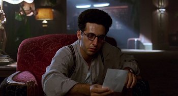 Movie still from “Barton Fink” (1991), directed by Joel Coen – A man sitting in a chair looking at a piece of paper; Close Up shot, Low angle